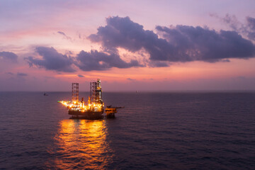 Aerial view of offshore jack up rig and offshore platform during sunset for oil and gas exploration and production.