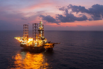 Aerial view of offshore jack up rig and offshore platform during sunset for oil and gas exploration and production.