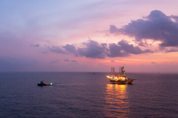 Aerial view of offshore jack up rig and offshore platform during sunset for oil and gas exploration and production.