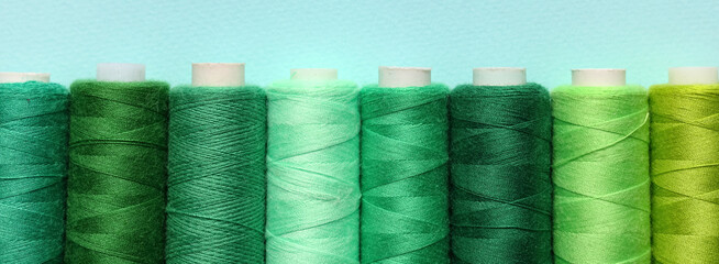 Spools of green thread on blue background