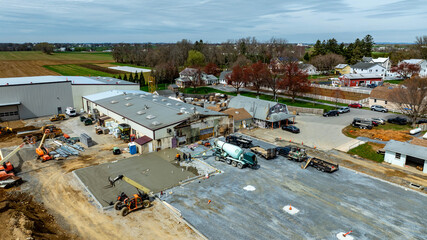 Construction Site in Rural Area With Workers and Machinery Performing Tasks on a Concrete Slab....