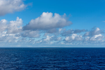 Obraz premium Minimal seascape with calm dark blue ocean and cloudy sky, abstract natural background with copy space and sense of calm.