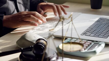 Close-up of hands typing on a laptop with justice scales and gavel in the foreground. Represents digital legal services, law firm, and online consulting.