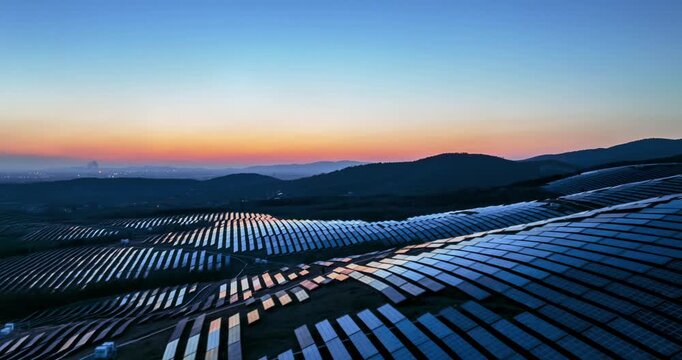Aerial time-lapse of solar power station on rolling hills during twilight, renewable energy landscape in blue hour