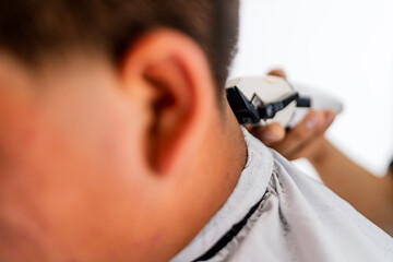 Barber cutting customer's hair with electric clippers