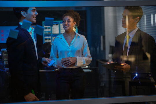 Tech startup founders mapping agile workflow on transparent board. Scrum master writing software development strategy while product owner reviews tasks during late night meeting. - Powered by Adobe