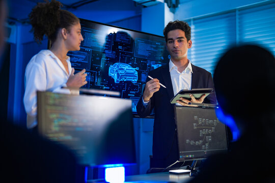 Autonomous driving software developers discussing car AI navigation system. IT specialist explaining self-driving vehicle simulation data to colleagues in modern control room. - Powered by Adobe