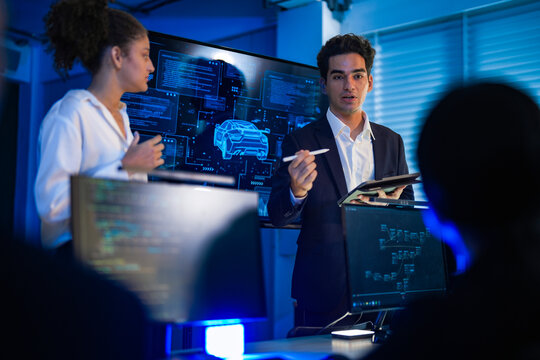 Autonomous driving software developers discussing car AI navigation system. IT specialist explaining self-driving vehicle simulation data to colleagues in modern control room. - Powered by Adobe