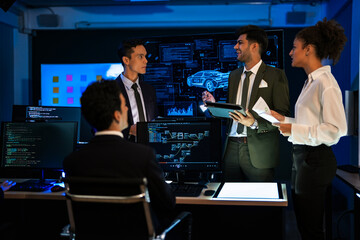 Automotive engineer presenting electric car design on large digital screen. Technical team analyzing vehicle aerodynamics and engine performance data in high-tech laboratory.