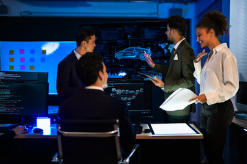 Autonomous driving software developers discussing car AI navigation system. IT specialist explaining self-driving vehicle simulation data to colleagues in modern control room.