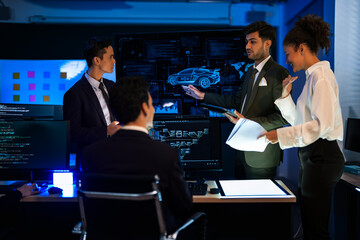 Autonomous driving software developers discussing car AI navigation system. IT specialist explaining self-driving vehicle simulation data to colleagues in modern control room.