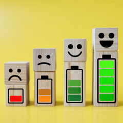 Four wooden blocks stacked showing battery levels and facial expressions