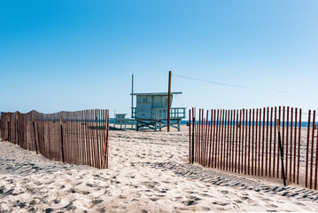 View through a sand fence towards a white lifeguard stand on the Californian coast