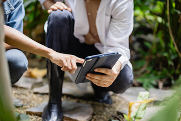 Young agricultural research team is working in farm using tablet to analyze data and collaborate closely on scientific study with focus and dedication in natural outdoor setting