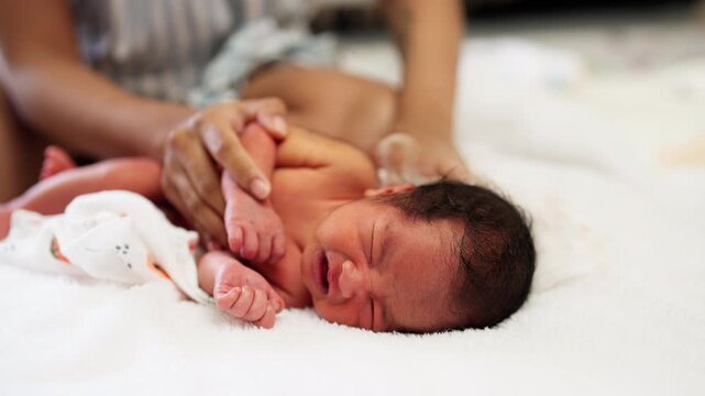 A newborn being gently comforted while crying after a bath. The moment captures early caregiving and tender love in a baby's first days.
