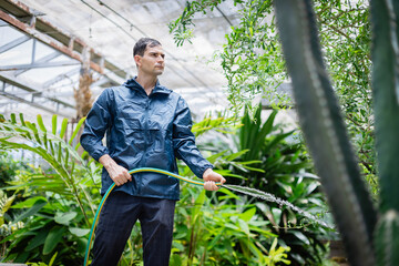 Young scientist in farm greenhouse is part of agricultural research team carefully watering plants to support growth and study in controlled environment with dedication and focus