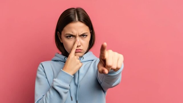 Young Girl Showing Distrust and Pointing Accusingly Against Pink Backdrop