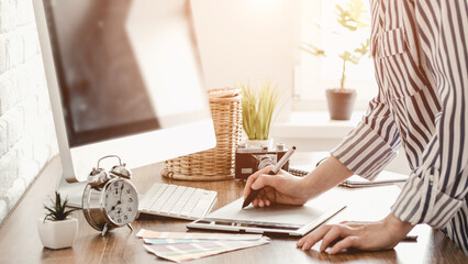 Young female designer using graphics tablet while working with computer