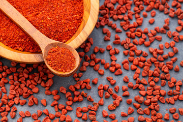 Ground or crushed organic annatto in the spoon and in the bowl - Bixa orellana