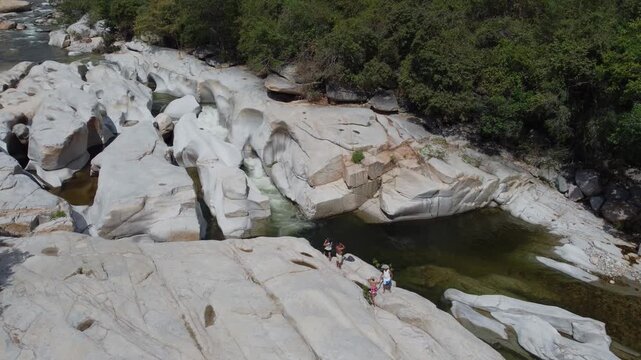 Aerial view of Badillo River in Valledupar, Colombia, with people swimming among iconic giant white rocks.