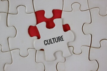 Fototapeta premium A white jigsaw background with a single puzzle piece labeled CULTURE resting on an red underlay.