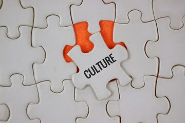 Fototapeta premium A white jigsaw background with a single puzzle piece labeled CULTURE resting on an orange underlay.