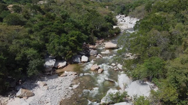 Aerial view of Badillo River in Valledupar, Colombia, with people swimming among iconic giant white rocks.