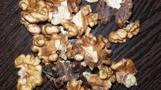 A tight close-up of a walnut kernel on a table, revealing the nutrient-rich meat freed from its natural shell and showcasing its distinctive texture, warm golden tones, and intricate folds