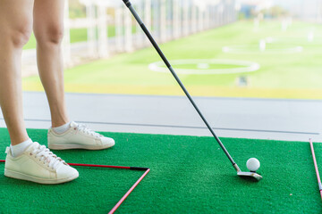 Close up of golfer preparing to hit golf ball on turf at driving range
