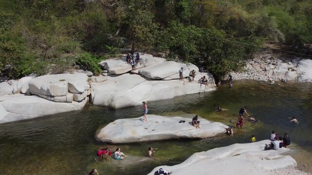 Aerial view of Badillo River in Valledupar, Colombia, with people swimming among iconic giant white rocks.
