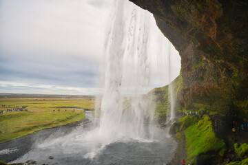Majestic Seljalandsfoss waterfall in Iceland, where powerful cascades of crystal-clear water plunge from towering cliffs into a misty pool below.