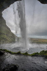 Majestic Seljalandsfoss waterfall in Iceland, where powerful cascades of crystal-clear water plunge from towering cliffs into a misty pool below.