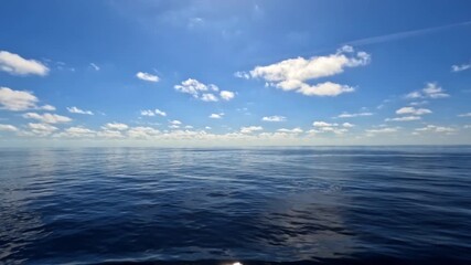 White clouds in blue sky and ocean with calm waters. Sailboat traveling in open sea during vacation. Cruise ship sailing - Powered by Adobe