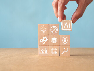 Hand placing AI wooden block on stack with business icons. Artificial intelligence, machine learning, and digital transformation concept for technology strategy on blue background with copy space.