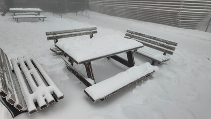 Snow covers picnic table in park during winter season