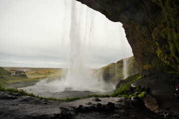Majestic Seljalandsfoss waterfall in Iceland, where powerful cascades of crystal-clear water plunge from towering cliffs into a misty pool below.