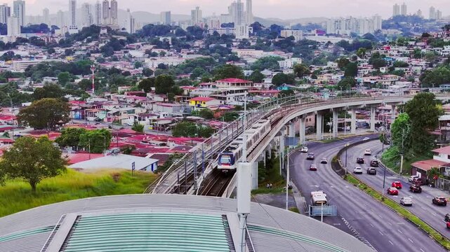 Aerial shot of a train leaving one of the elevated metro lines in Panama with a view of the city in the background