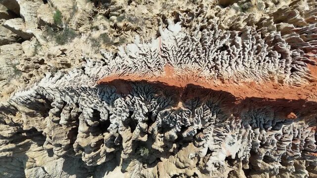 Close-range aerial drone shot of the intricate erosion patterns and bright orange colors of the Miradouro da Lua cliffs in Angola, Africa travel destination