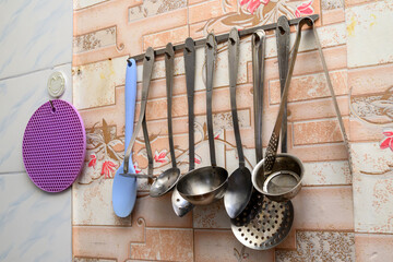 kitchen utensils and a purple trivet on the wall