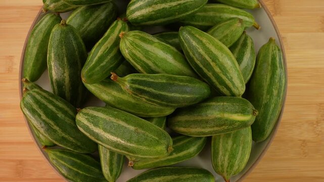 Fresh pointed gourd on a plate rotation top view. Selective focus. Parwal.