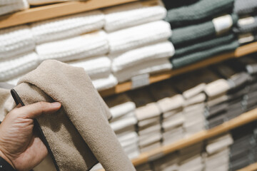 Hand touching a grey textured bath mat or towel on a store shelf.