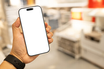 Man hand holding smartphone with blank white screen in blurred warehouse background, AI logistics and inventory management concept. Supply chain logistics, smart warehousing, and online shopping.