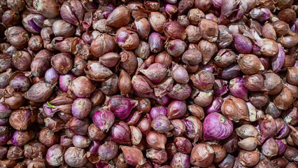 Red shallots piled together creating natural food texture background.
