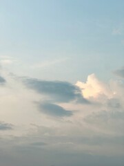 A vertical shot of a bright, clear blue sky with soft white and grey cumulus clouds, ideal for a background or nature-themed design.