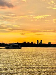 Fototapeta premium A wide landscape of a vibrant golden sunset over a body of water, likely Putrajaya Lake.