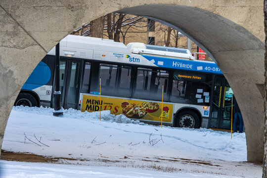 Canada, Montreal, 24 December 2025 : Bus passing under bridge during snowy winter day scene