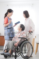 在宅介護や訪問介護のデイサービスのイメージで訪問する看護師と後期高齢者の女性と家族　訪問介護の計画などをタブレットで案内する