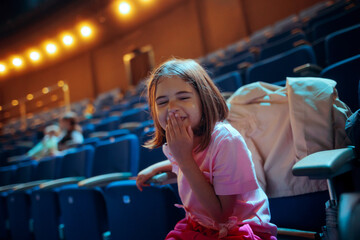 Little Girl Laughs at the Circus and Waits for the Show to Start. Spectator in the audience enjoying entertainment performance about to begin