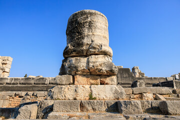 Fototapeta premium Ancient stone column ruin against clear blue sky in historic archaeological site