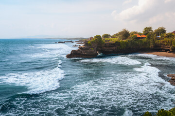 Tanah Lot temple Bali ocean waves crashing rock, iconic Hindu shrine on cliff amid turquoise sea...